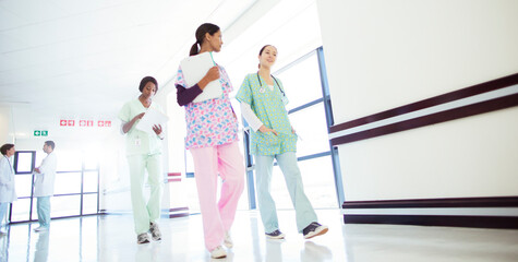 Fototapeta na wymiar Nurses talking and walking in hospital corridor