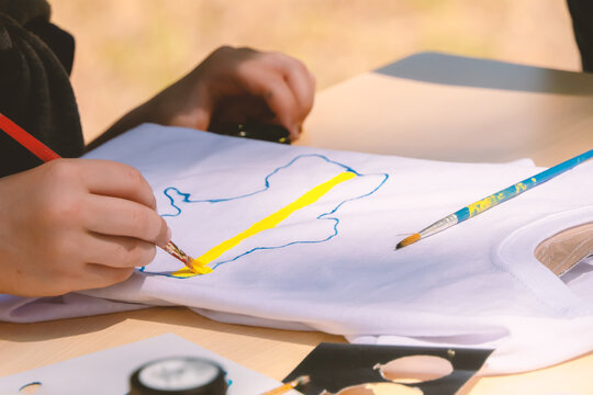 Children draw a map of Ukraine on a T-shirt.