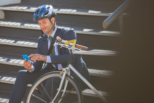 Businessman in suit bicycle helmet texting cell phone on stairs