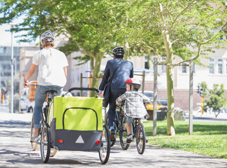Families riding bicycles in sunny urban park