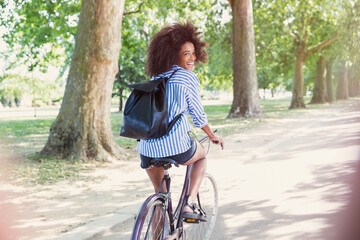 Portrait smiling woman with afro riding bicycle in park