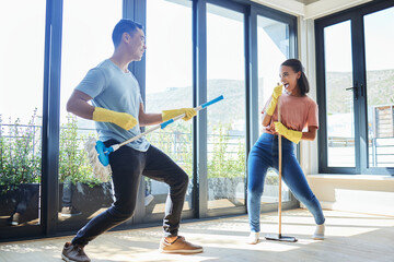 Couple, singing and cleaning home, dance and having fun playing with mop guitar and broom. Clean, dancing and happy man and woman, singer and chores, housekeeping together and happiness for music.