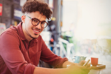 Portrait smiling man with curly black hair texting in cafe