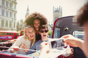 Enthusiastic friends being photographed on double-decker bus - obrazy, fototapety, plakaty
