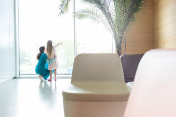 Nurse with pointing girl at hospital lobby window