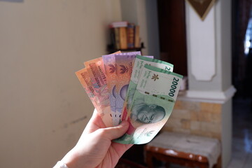 New issuance of Indonesian Rupiah Banknotes in 2022. Hand holding rupiah banknotes with a nominal value of five thousand, ten thousand and twenty thousand.