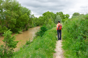 Fototapeta na wymiar woman hiker with backpack on the path by the river