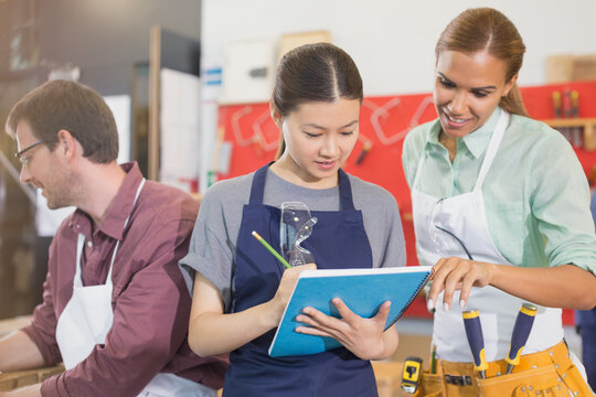 Female carpenters reviewing plans in workshop