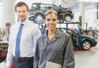 Portrait confident businessman and female mechanic in auto repair shop