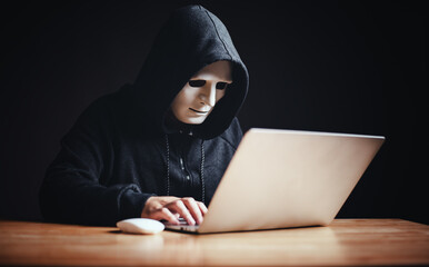 Black hat hacker in hood using tablet on desk to hacking privacy sensitive data cyber crime hack in dark room background matrix binary code. Cyber security cyber crime concept. Hacking phishing