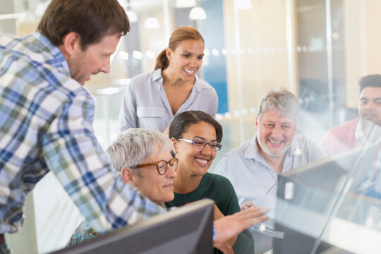 Smiling students at computer in adult education classroom - Powered by Adobe