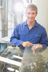 Fototapeta Portrait confident mechanic working on engine in auto repair shop obraz