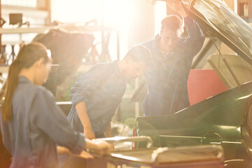 Mechanics looking inside trunk in auto repair shop