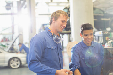 Smiling mechanics using computer in auto repair shop