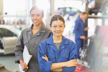 Portrait confident female mechanics in auto repair shop
