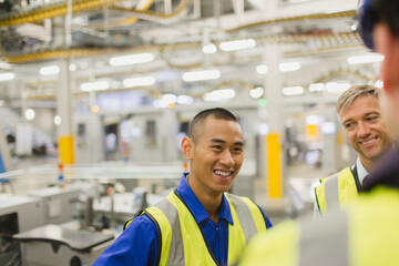 Workers in reflective clothing talking in factory