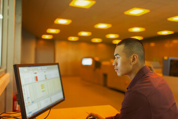 Engineer working at computer in factory control room