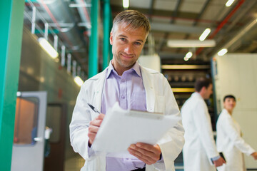 Portrait confident scientist with clipboard in factory