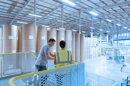 Workers talking on platform above factory