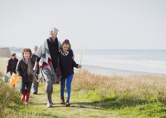 Multi-generation family walking on grassy beach path - obrazy, fototapety, plakaty