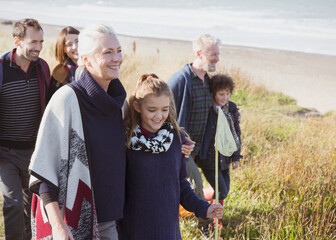 Smiling multi-generation family walking in beach grass - Powered by Adobe
