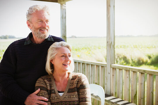 Smiling senior couple looking away on sunny porch