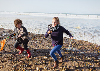 Brother and sister with nets running from ocean onto beach