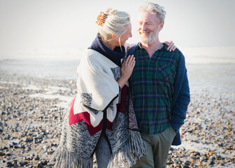 Senior couple hugging and walking on sunny rocky beach