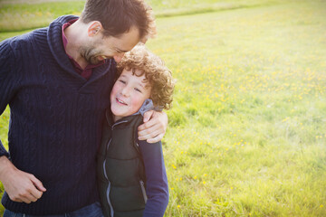 Obraz premium Father hugging son in field