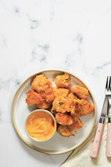Crispy salmon bites with spicy mayo sauce, baked. White and wooden background