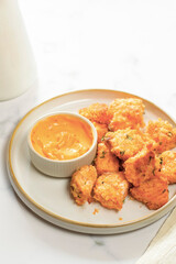 Crispy salmon bites with spicy mayo sauce, baked. White and wooden background