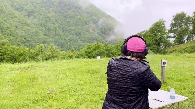 Woman Skeet Shooting with a Shotgun in a Outdoor Shooting Range.