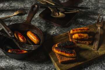 Still life fried sausages in a cast-iron pan on a dark background