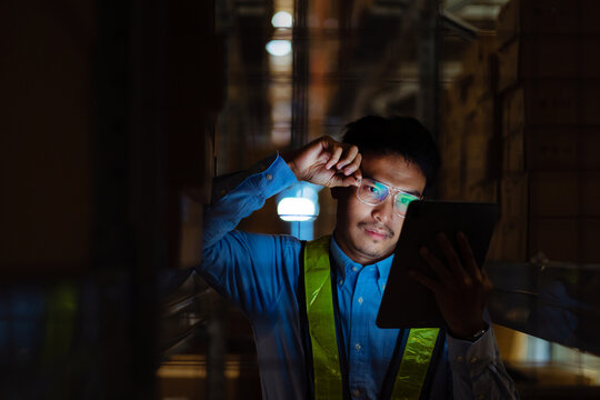 Asian male warehouse worker feeling sad and stressed at work. work stress Malfunctioning.