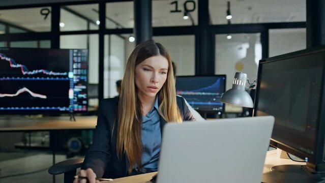 Finance broker working computer at investment graph. Focused woman analyze stock
