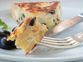 Close-up of tortilla with black olives and feta cheese on a fork