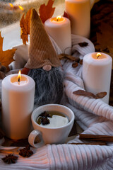 Thanksgiving and Hello Fall Halloween concept Celebrating autumn holidays at cozy home on the windowsill Hygge aesthetic atmosphere Autumn leaves gnome, spices and candle on knitted white sweater in