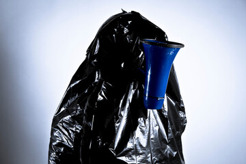 Person with a black garbage bag on and megaphone in mouth