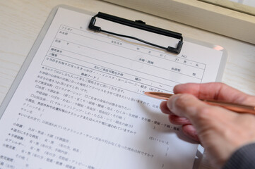 カルテ（問診票）に書き込む女性の手元　右利き　カウンセリング　美容サロン