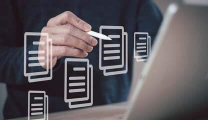 Businessman working on laptop computer with electronics document icons, E-document management, online documentation database, paperless office concept.