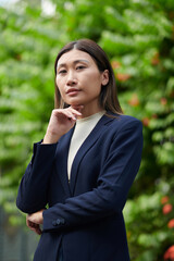 Confident successful businesswoman standing outdoors and looking down at camera