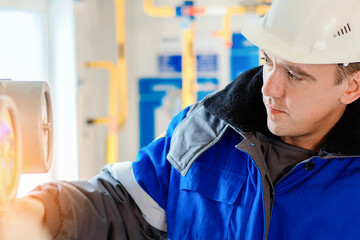 Close-up portrait of worker in hard hat and winter overalls. Authentic workflow. Gas equipment repairman at work. Professional diagnostics and adjustment of equipment.