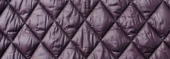 Quilted fabric background texture blanket or puffer jacket.padded, down jacket. Background of urban winter outfit.Quilted pattern.Banner.