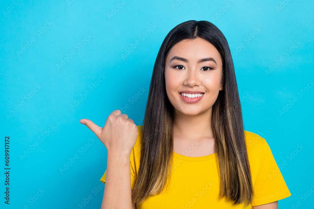 Sticker Photo of attractive asian girl directing thumb finger empty space adv ads banner news isolated bright blue cyan color background