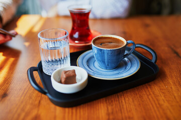 Traditional Turkish coffee and tea served with glass of water and chocolate sweet in cafe or restaurant in Istanbul