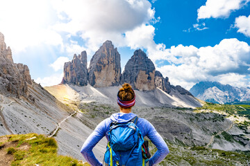 Young athletic woman enjoys view on Tre Cime mountain rangeat noon. Tre Cime, Dolomites, South Tirol, Italy, Europe.