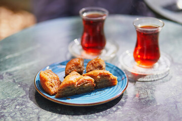 Turkish tea served in tulip shaped glasses with baklava sweets in cafe or restaurant in Istanbul, Turkey