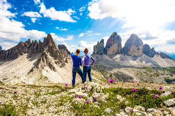 Young athletic couple enjoys scenic view on Monte Paterno and Tre Cime in the afternoon. Tre Cime, Dolomites, South Tirol, Italy, Europe. - obrazy, fototapety, plakaty