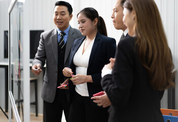 Businessperson teamwork meeting in office and use sticky post notes to brainstorming ideas on glass board. Asian businesswoman planning corporate strategy with colleague for success startup business.