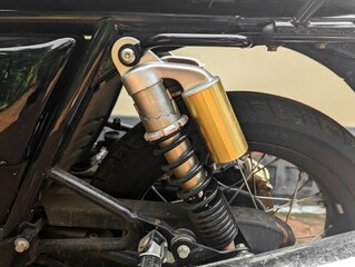 a pneumatic gas charged shock absorber coil spring suspension fixed at the rear of a motorcycle frame - obrazy, fototapety, plakaty